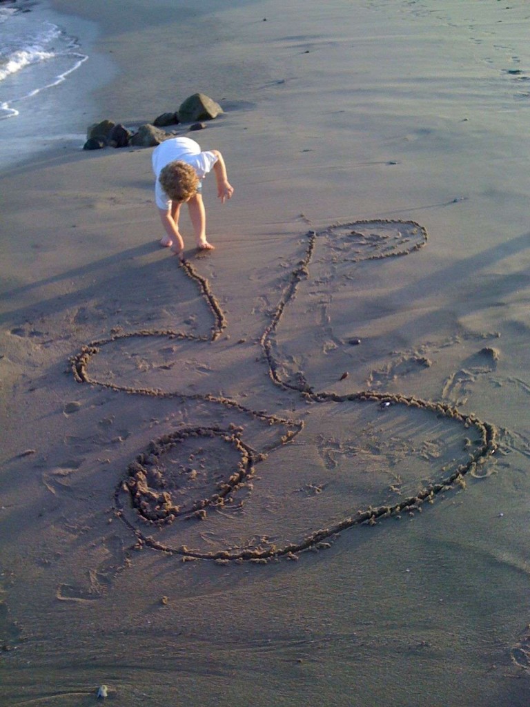 child drawing in sand